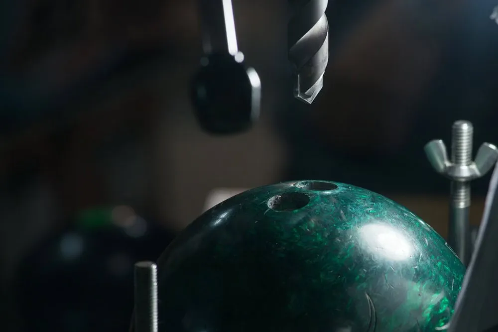 Close up of drilling a bowling ball with drill bit and hammer for custom fitting